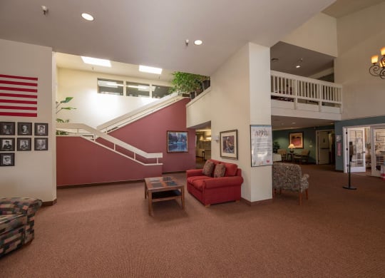 a living room with a red couch and a staircase at Hilltop Commons Senior Living, California