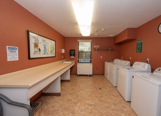 a washer and dryer room with a row of washing machines at Hilltop Commons Senior Living, Grass Valley, 95945