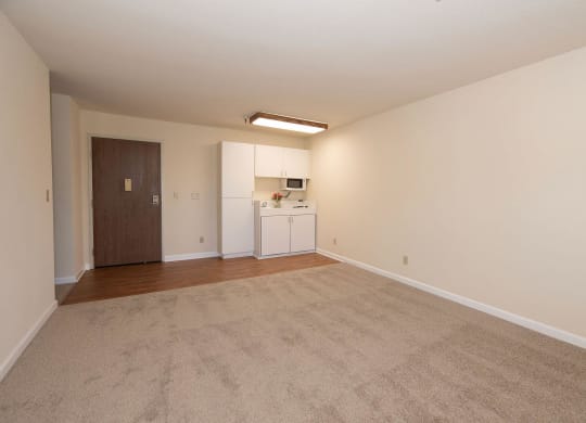 an empty living room with a kitchen in the background at Hilltop Commons Senior Living, Grass Valley, CA