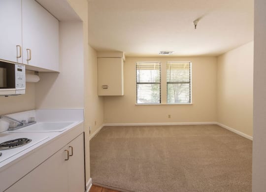 an empty kitchen with white cabinets and a window at Hilltop Commons Senior Living, Grass Valley California