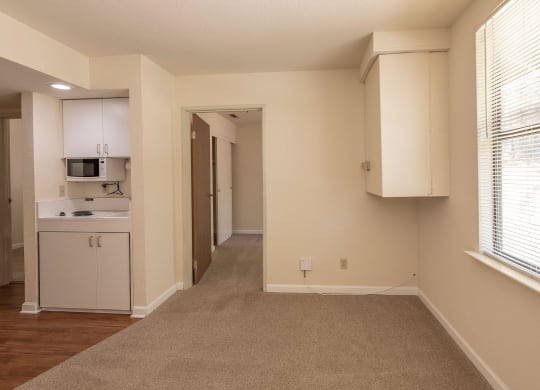 an empty room with a kitchen and a large window at Hilltop Commons Senior Living, California, 95945