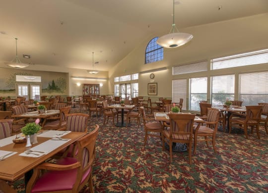 a large dining room with tables and chairs and windows at Hilltop Commons Senior Living, Grass Valley California