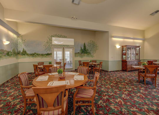 a conference room with tables and chairs and a painting on the wall at Hilltop Commons Senior Living, Grass Valley