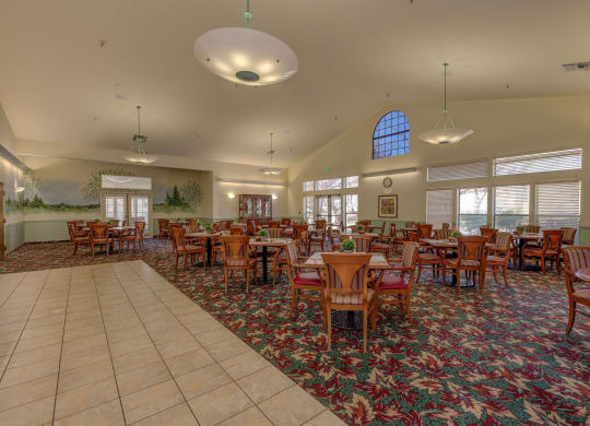 a large dining room with tables and chairs in arium at Hilltop Commons Senior Living, California