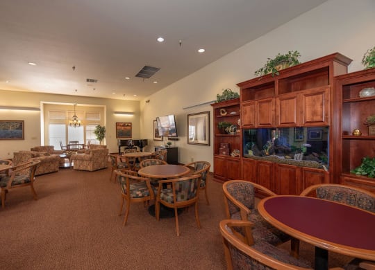 a living room with tables and chairs and a fish tank at Hilltop Commons Senior Living, California