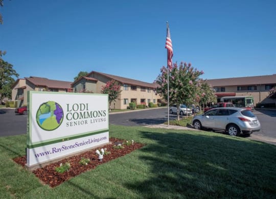 Front entrance to Lodi Commons with sign and grassy knoll at Lodi Commons Senior Living, Lodi, CA 95240