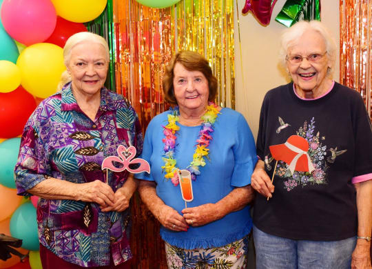 three women standing in front of balloons at a party at River Commons Senior Living, Redding, CA 96002