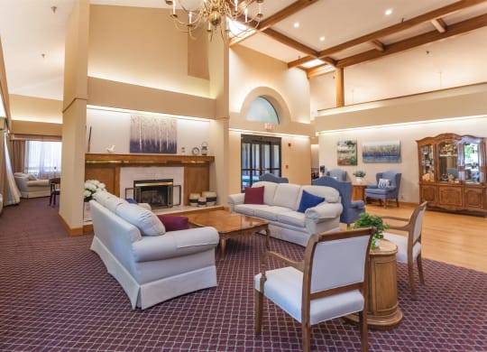 a living room with couches and chairs and a fireplace at River Commons Senior Living, California