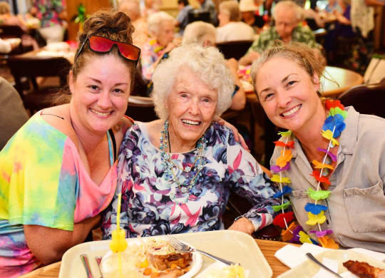 three women sitting at a table with a plate of food at River Commons Senior Living, Redding