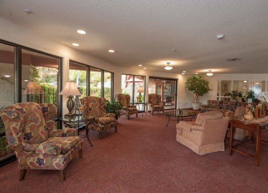 a living room filled with furniture and large windows at Roseville Commons Senior Living, Roseville California