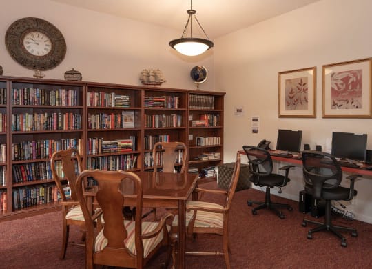 a library with a desk and chairs and a table with bookshelves at Roseville Commons Senior Living, Roseville