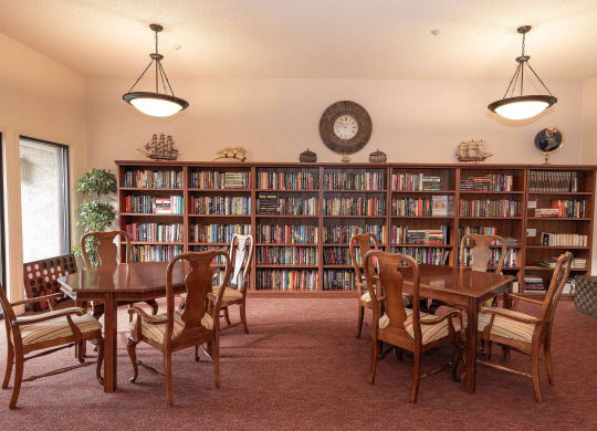 a library with a table and chairs and shelves of books at Roseville Commons Senior Living, Roseville, CA 95678