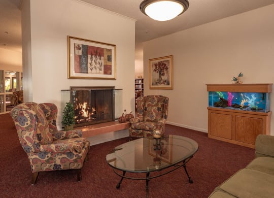 a living room with a fireplace and a table and chairs at Roseville Commons Senior Living, California