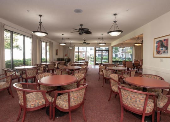 a group of tables and chairs in a room with windows at Roseville Commons Senior Living, Roseville, 95678