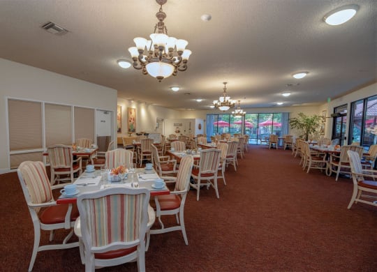 a dining room with tables and chairs and a chandelier at Roseville Commons Senior Living, Roseville, CA 95678