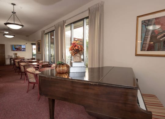 a living room with a piano and a dining room with tables and chairs at Roseville Commons Senior Living, Roseville California
