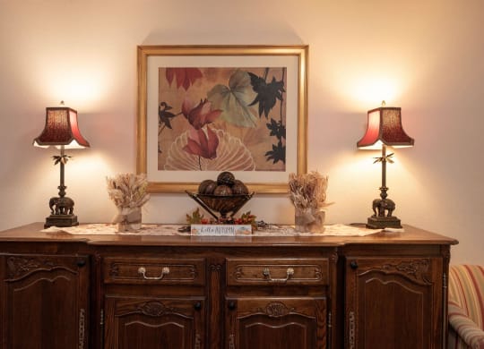 a side table with two lamps and a picture on the wall at Roseville Commons Senior Living, California