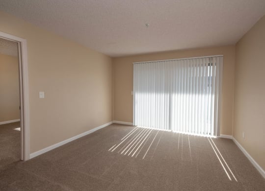 an empty living room with a large window and blinds at Roseville Commons Senior Living, Roseville California