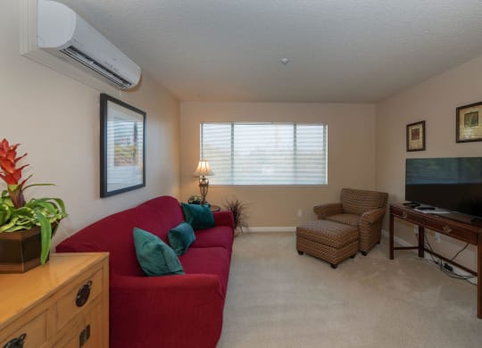 a living room with a red couch and a tv at Roseville Commons Senior Living, California, 95678