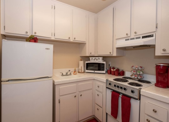 a kitchen with white cabinets and appliances and a white refrigerator at Roseville Commons Senior Living, Roseville