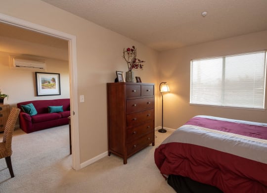 a bedroom with a bed and a living room with a couch at Roseville Commons Senior Living, California