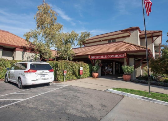 a car parked in front of a building with an flag at Roseville Commons Senior Living, California, 95678