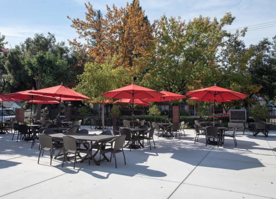 a patio with tables and umbrellas at Roseville Commons Senior Living, Roseville, CA 95678