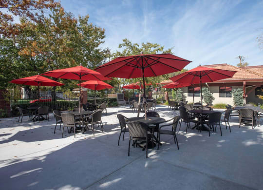a patio with tables and umbrellas at Roseville Commons Senior Living, California