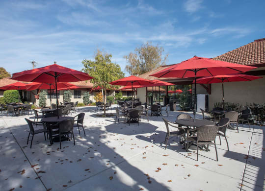 a patio with tables and chairs and umbrellas at Roseville Commons Senior Living, Roseville, CA 