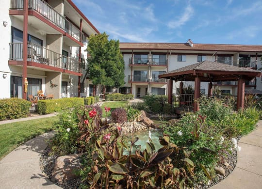 a courtyard with a garden in front of an apartment building at Roseville Commons Senior Living, Roseville California