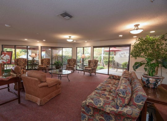 a large room with chairs and tables and windows at Roseville Commons Senior Living, California