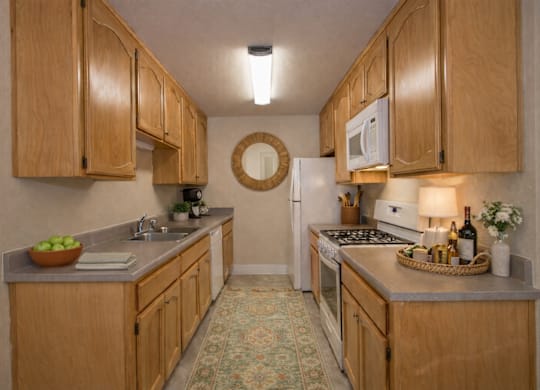 Galley kitchen with oak cabinets and white appliances at Castle Vista Senior Duplex Community Apartments, Atwater