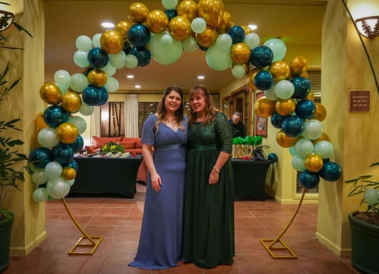 two women standing under a balloon arch at a party at Winding Commons Senior Living, Carmichael, CA