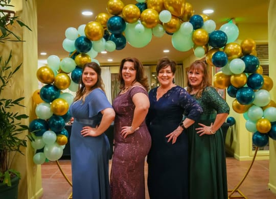 a group of women standing in front of a balloon arch at Winding Commons Senior Living, Carmichael, CA, 95608