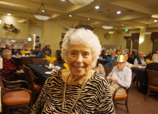an older woman standing in front of a group of people sitting at tables at Winding Commons Senior Living, Carmichael, CA