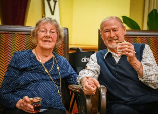 an older man and woman sitting in a chair eating food at Winding Commons Senior Living, Carmichael, CA, 95608