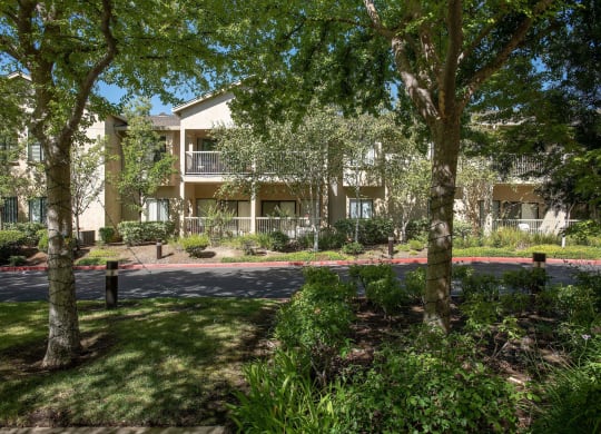 an exterior view of an apartment building with trees at Winding Commons Senior Living, Carmichael, California