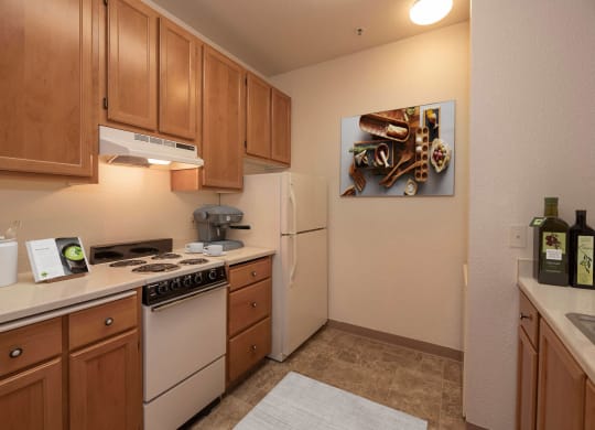 a kitchen with white appliances and wooden cabinets at Winding Commons Senior Living, Carmichael, CA, 95608