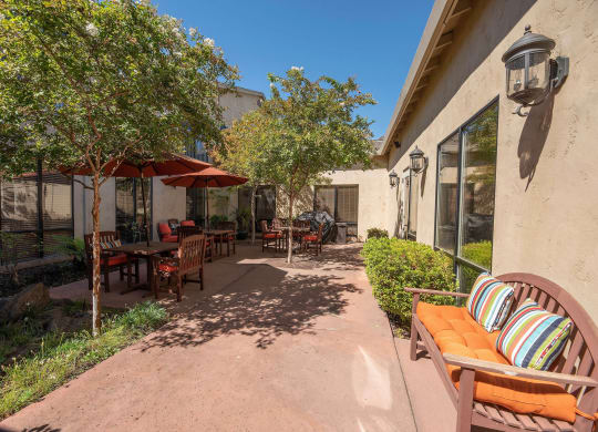 a patio with tables and chairs and umbrellas at Winding Commons Senior Living, Carmichael, CA, 95608