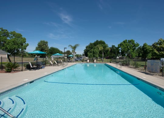 a swimming pool with trees in the background and a blue sky at Castle Vista Senior Duplex Community, Atwater, 95301