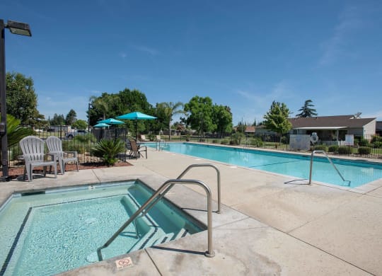 our apartments have a swimming pool with chairs and umbrellas at Castle Vista Senior Duplex Community, Atwater, CA