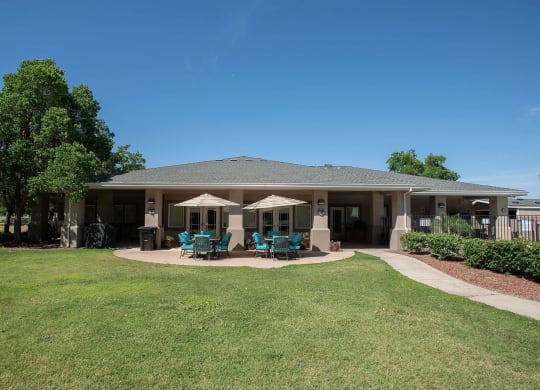 the backyard of a house with patio chairs and umbrellas at Castle Vista Senior Duplex Community, Atwater, CA