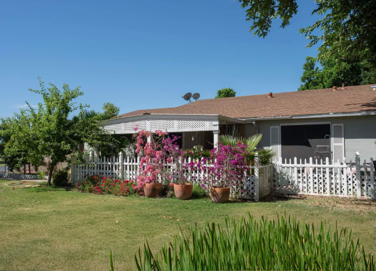 a house with potted flowers in front of a white fence at Castle Vista Senior Duplex Community, Atwater, CA, 95301
