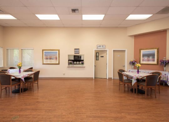 a dining room with tables and chairs in a large room with a wood floor at Castle Vista Senior Duplex Community, Atwater, CA, 95301