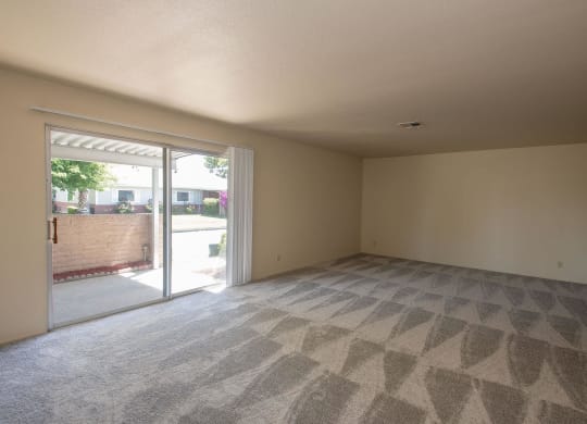 an empty living room with sliding glass doors to a patio at Castle Vista Senior Duplex Community, Atwater