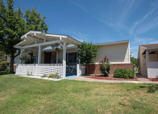 a white house with a lawn and a white picket fence at Castle Vista Senior Duplex Community, Atwater, California
