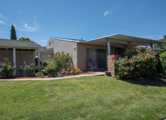 a view of the front of a house with a lawn and flowers at Castle Vista Senior Duplex Community, Atwater, CA