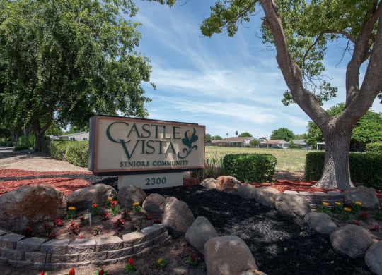 a sign in front of a tree and rocks at Castle Vista Senior Duplex Community, Atwater, California