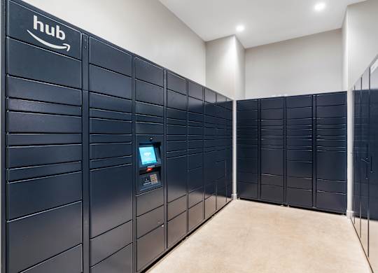 a row of navy blue parcel lockers in a room with a computer in the middle at Textile Apartments, Cincinnati, OH, 45202