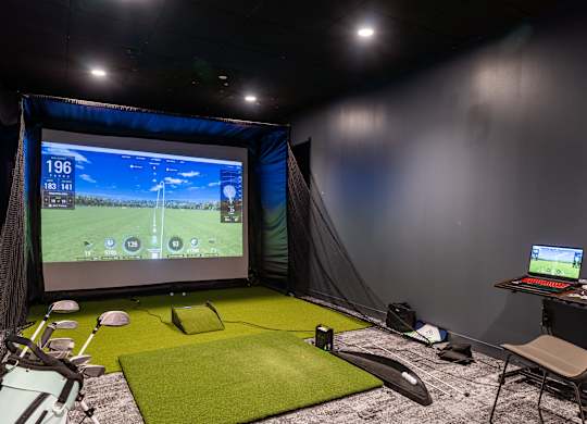 a home cinema with a screen and a green carpet floor and a desk  at Textile Apartments, Cincinnati, Ohio